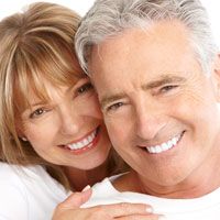 An older couple smiles to show off their porcelain veneers